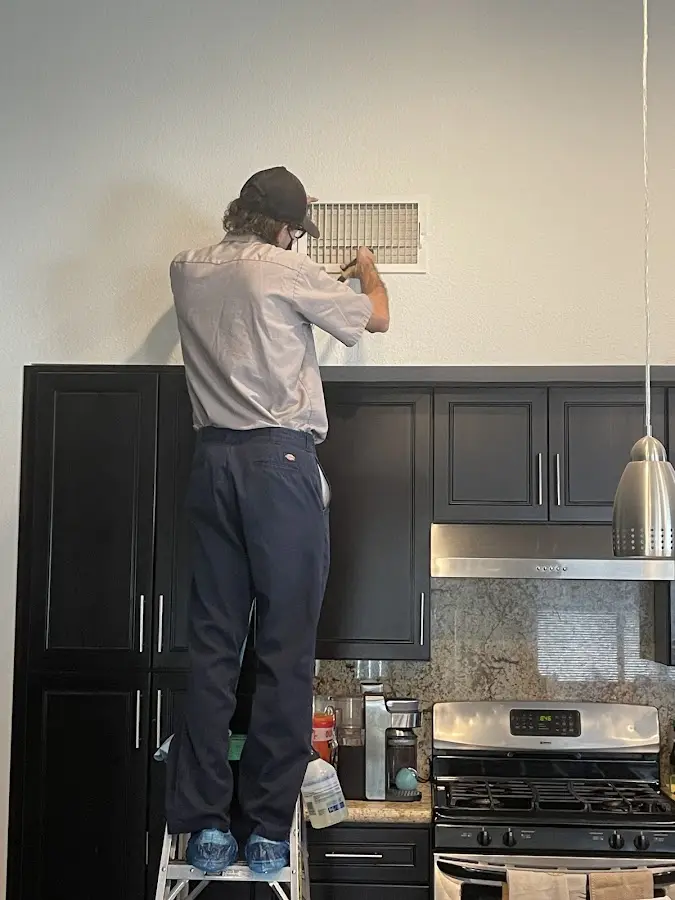 Technician inspecting an air vent during HVAC service in Archbald